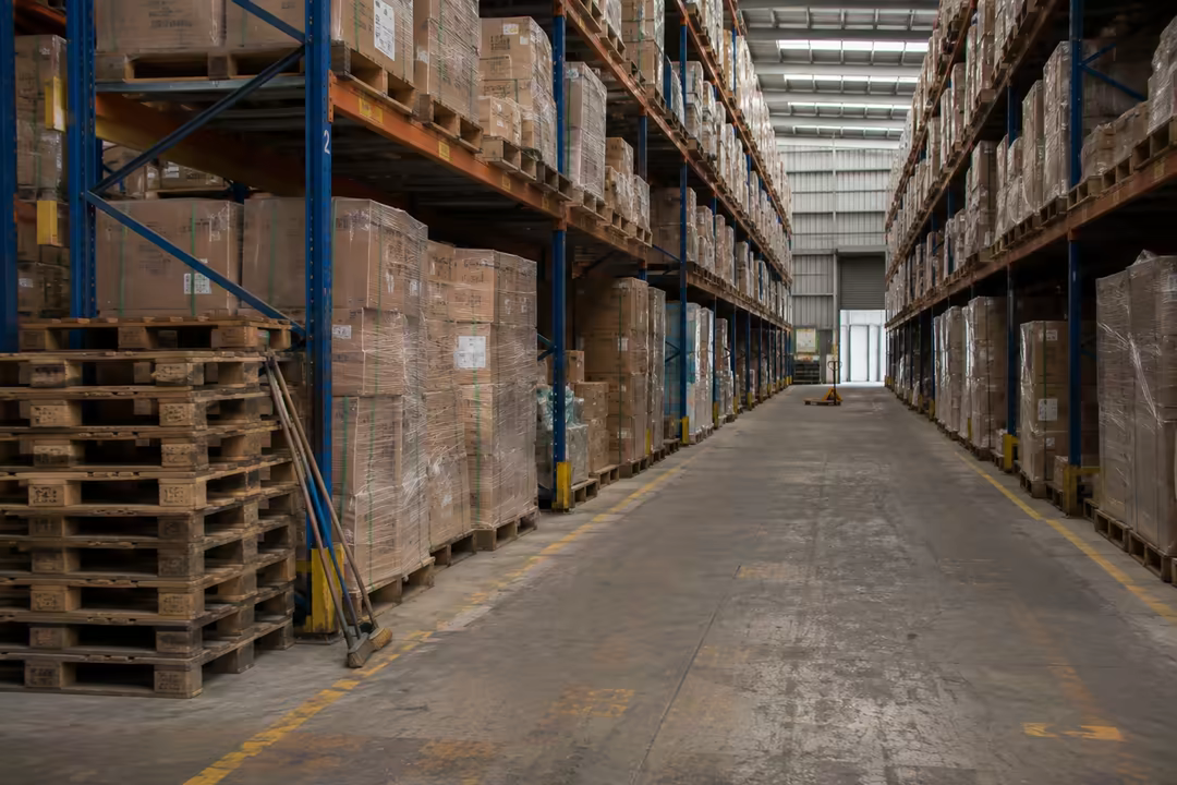 Warehouse aisle with empty pallets stacked beside the racking